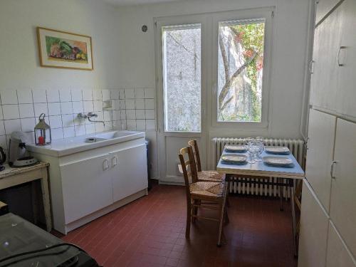 uma cozinha com uma mesa, um lavatório e uma janela em LES VOLETS BLEUS em Metz