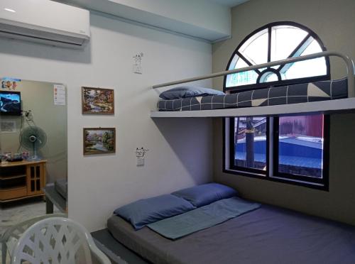 Zimmer mit 2 Etagenbetten und einem Fenster in der Unterkunft Thian Siong Inn in Malakka