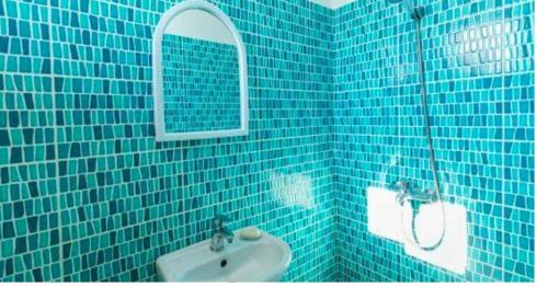 a blue tiled bathroom with a sink and a mirror at Apartament Kaçanik in Vitina