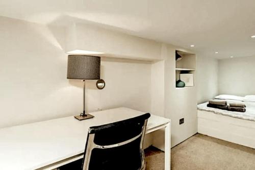 een slaapkamer met een bureau met een lamp en een bed bij Live the London life in Notting hill in Londen