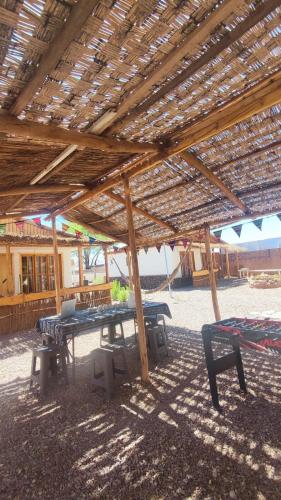 a picnic table and chairs under a wooden roof at Cabañas Voyage Atacama in San Pedro de Atacama