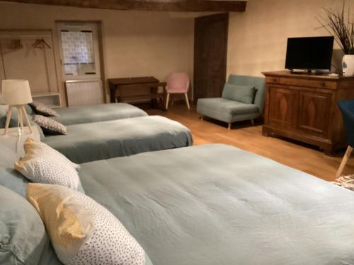 a room with two beds and a chair and a television at Maison Allianes in Avrilly