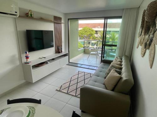 un soggiorno con divano e TV di Luxo à Beira-Mar - Flat 2 Quartos no Carneiros Beach Resort a Praia dos Carneiros