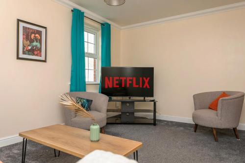 a living room with a tv and two chairs at The Durham House in Leyland