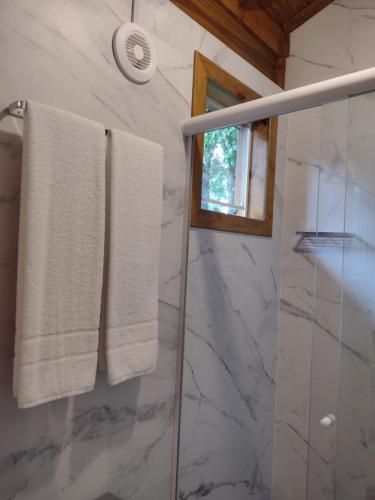 uma casa de banho com toalhas brancas e um chuveiro em Morada Bem Me Quer em Canela