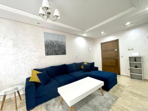 sala de estar con sofá azul y mesa en Appartement Tanger Moulay Ismail, en Tánger