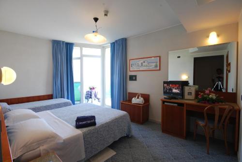 a hotel room with a bed and a desk and a mirror at Hotel Meripol in Alba Adriatica