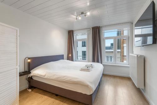 a bedroom with a large bed and two windows at Seaside 27 - De perfecte familie vakantiewoning aan zee voor 10p in Blankenberge