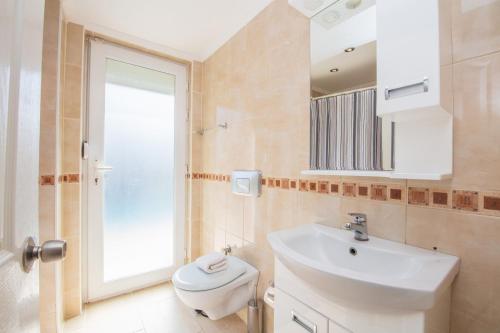 a bathroom with a sink and a toilet and a mirror at Golden Trio Villa in Oludeniz