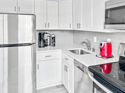 a kitchen with white cabinets and a red appliance at Stylish & Cozy Home Close To Beach- Free Parking, Private, Backyard, Laundry in Pompano Beach