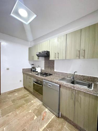a kitchen with wooden cabinets and a sink at Appartement Tanger Moulay Ismail in Tangier