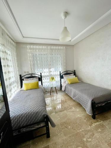 a bedroom with two beds and a window at Appartement Tanger Moulay Ismail in Tangier