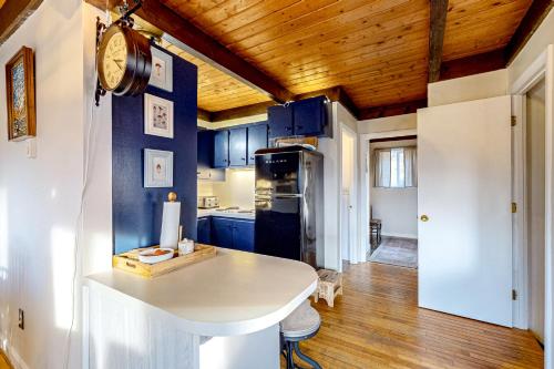 uma cozinha com armários azuis e um relógio na parede em Cozy Country Cottage em Whitefield