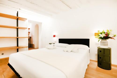 a white bedroom with a white bed and a vase of flowers at Santa Margherita, casa accogliente e confortevole in Venice