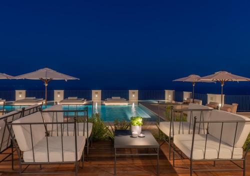 a hotel pool with chairs and umbrellas at night at Furore Grand Hotel in Furore