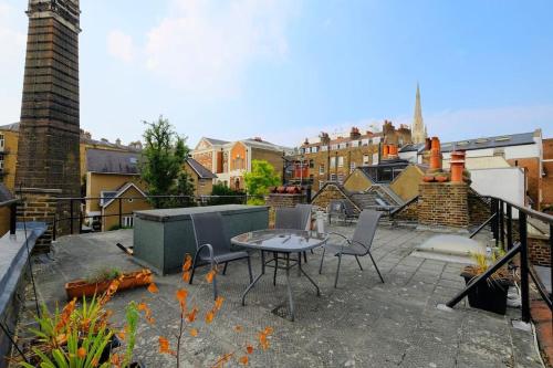 a patio with a table and chairs on a balcony at Roof Terrace Flat in Hampstead Pass The Keys in London