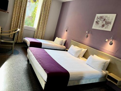 オランジュにあるCitHôtel Le Louvreの紫の壁のホテルルーム内のベッド2台
