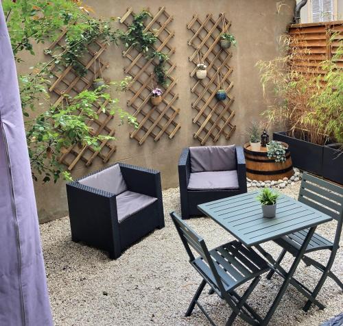 a patio with a table and chairs in front of a wall at Le Divio - Homillesime in Dijon