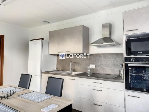 une cuisine avec des armoires blanches et une table avec des chaises dans l'établissement Maison 8 personnes à la campagne à 8 km des plages, à Notre-Dame-de-Riez