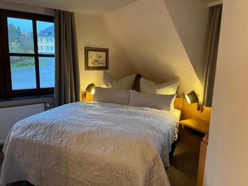 1 dormitorio con cama blanca y ventana en Hotel zum Forsthaus, en Willingen