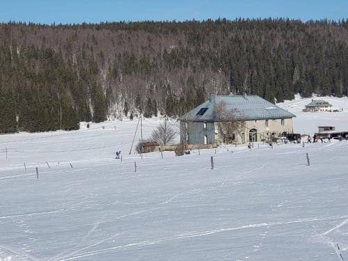 a barn in a snow covered field with trees at La Fessette in Chapelle-des-Bois
