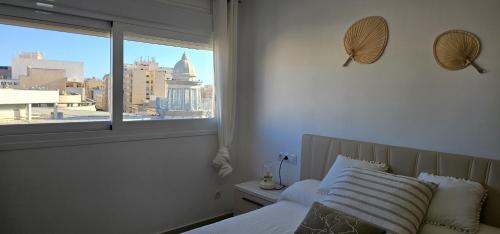 a bedroom with a bed with a view of a city at AlmeriaSuite City Centre in Almería