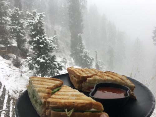 a black plate with sandwiches and a bowl of sauce at Odin Hostel Shoja in Shoja