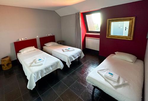 a room with two beds and a window at HI Serra da Estrela - Pousada de Juventude in Penhas da Saúde