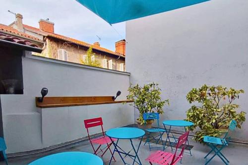 d'une terrasse avec des tables, des chaises et un parasol. dans l'établissement Villa Loha Maison de vacances, à Saint-Gaudens