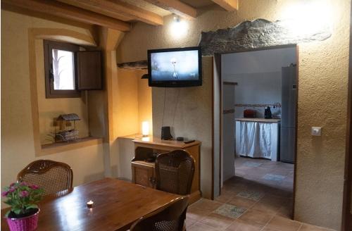 ein Esszimmer mit einem Tisch und einem TV an der Wand in der Unterkunft Masia Casa Nova de n'Illa in Montseny