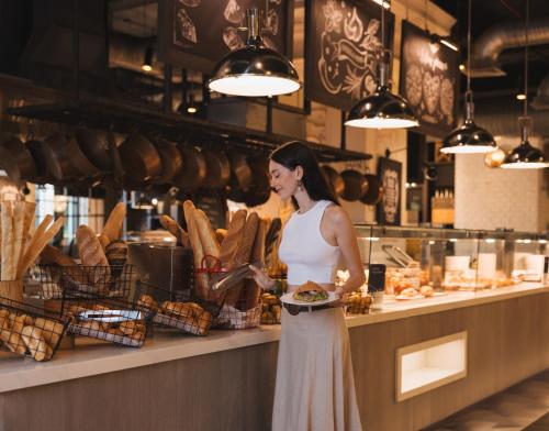 a woman standing in a bakery with a plate of bread at Hyatt Zilara Cap Cana - Adults Only in Punta Cana