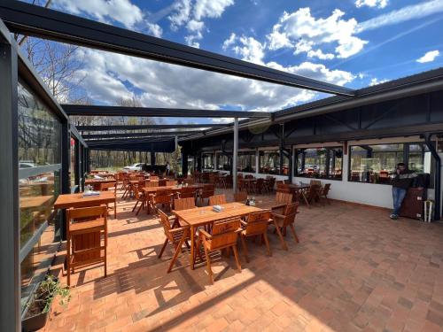 a restaurant with wooden tables and chairs and windows at Pastravaria Zavoi in Valea Danului