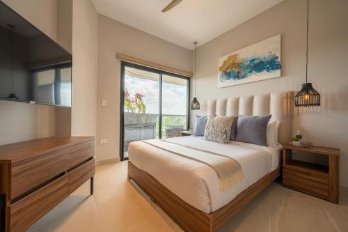 a bedroom with a large bed and a large window at Kippal - Modern Oasis - ApartHotel in Cozumel