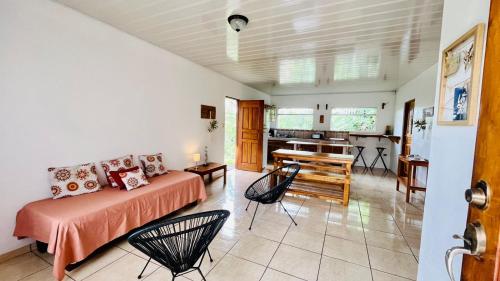 ein Wohnzimmer mit einem Bett und Stühlen sowie eine Küche in der Unterkunft Cozy coworking Casa Alma near Lake Arenal, 2 bedroom 1 office, fiber optic, pet friendly in Nuevo Arenal