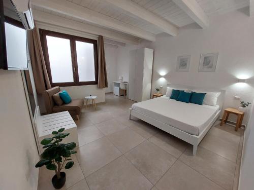 sypialnia z dużym białym łóżkiem i kanapą w obiekcie DoMe Affittacamere w mieście Iglesias