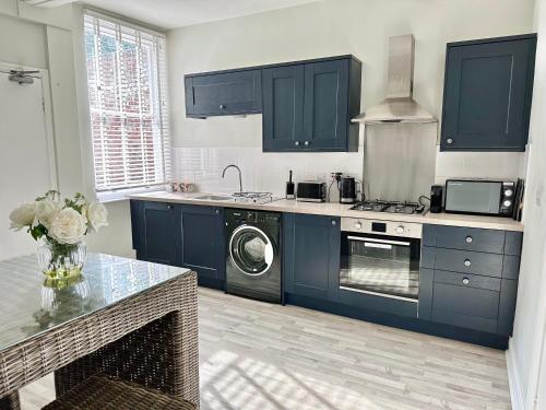 una cucina con armadi blu e lavatrice di Gillygate Nest with Free Allocated Parking a York