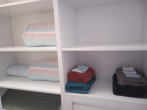 un armario con estanterías blancas y toallas plegadas en Casa en Jerez con patio cerca de la playa y de la sierra, en Jerez de la Frontera
