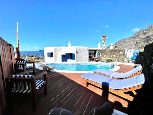 una terraza con piscina y sillas y una casa en Estupenda Villa con piscina privada, chimenea, frente al mar de Frontera, en La Frontera