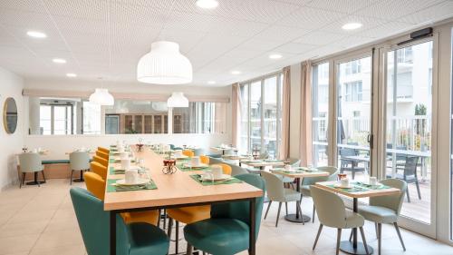 a dining room with tables and chairs and windows at Residhome Dijon Cité Des Vignes in Dijon