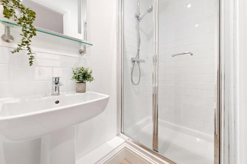 een witte badkamer met een wastafel en een douche bij The Market Street Studios in Nottingham
