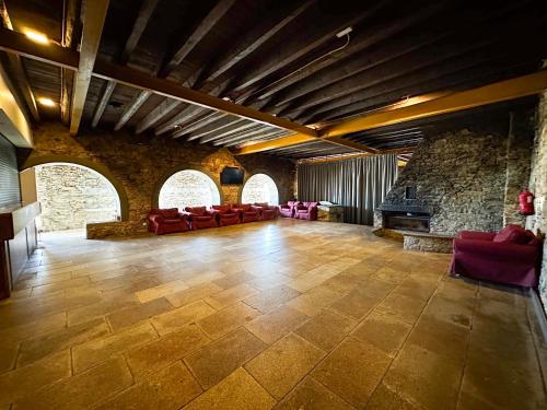 a large room with red chairs and a stone wall at HI Serra da Estrela - Pousada de Juventude in Penhas da Saúde