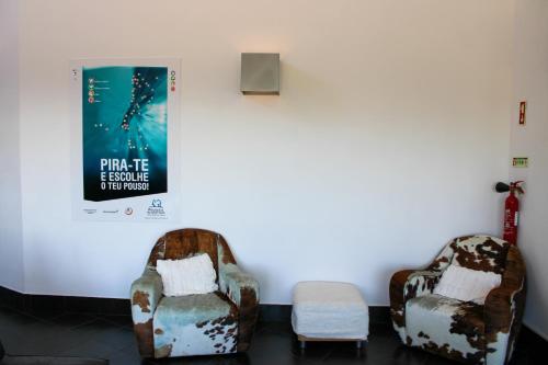 two chairs in a room with a poster on the wall at HI Serra da Estrela - Pousada de Juventude in Penhas da Saúde