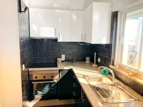 uma cozinha com armários brancos, um lavatório e uma janela em Shiny Apartment in the city center em Fuzeta