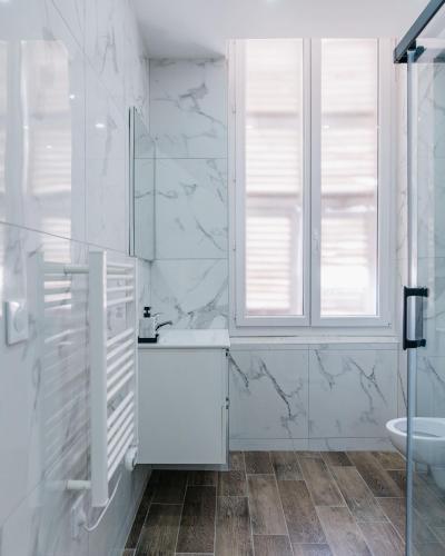 a white bathroom with a sink and a window at Studio Nicehome Massena in Nice