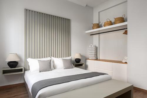 una camera da letto con un grande letto bianco con cuscini bianchi di KASO - Fotomara ad Atene