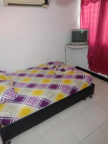 1 dormitorio con 1 cama y TV en la pared en Hotel el Manaa Santa Marta en Cúcuta