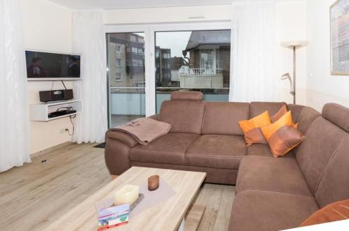 - un salon avec un canapé brun et une table dans l'établissement Wehrbergsdüne 26, FeWo 4, à Duhnen