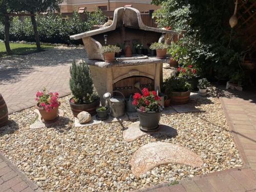 a garden with a stone fireplace and potted plants at Rozmann Family Panzió & Apartmanhaz in Sárvár
