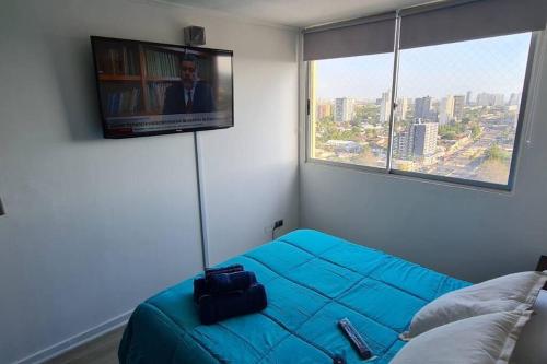 a bedroom with a blue bed and a large window at Departamento Vista hermosa in Santiago