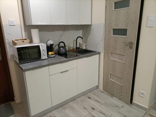 a small kitchen with a microwave and a sink at Apartament Kościuszko in Malbork